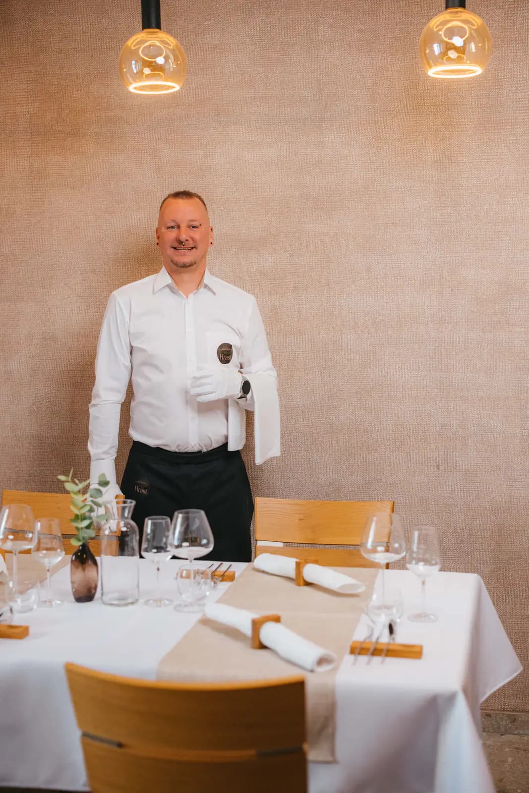 Smiling Gostilna Hrast team member in the prepared dining room